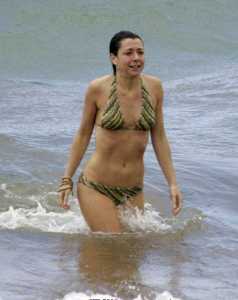 Alyson marche vers la plage alors qu'une vague se forme derrire elle